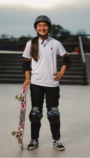 Person standing with skateboard while wearing protective gear.